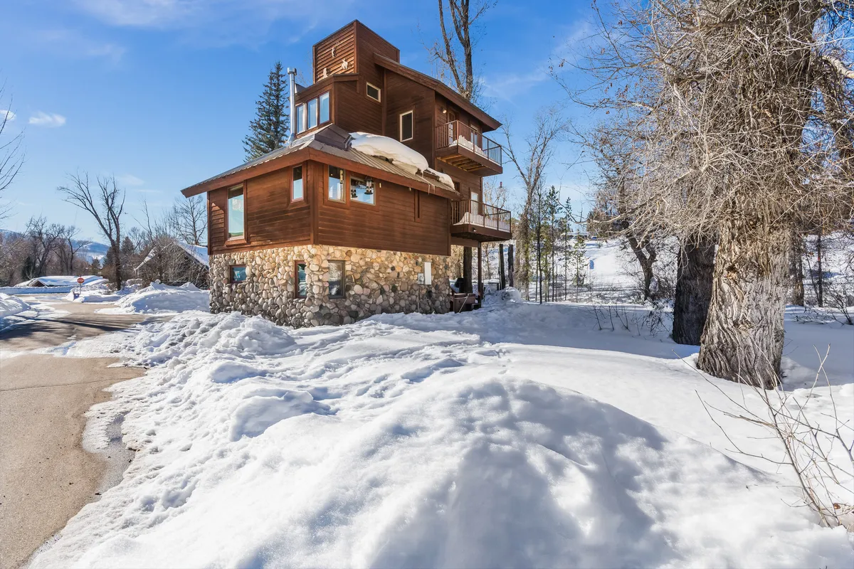 A wide exterior shot of the home’s wooden and stone structure, with multiple balconies overlooking a snow-blanketed landscape. The image suggests opportunities for outdoor relaxation and reflects the house's integration with its natural surroundings.